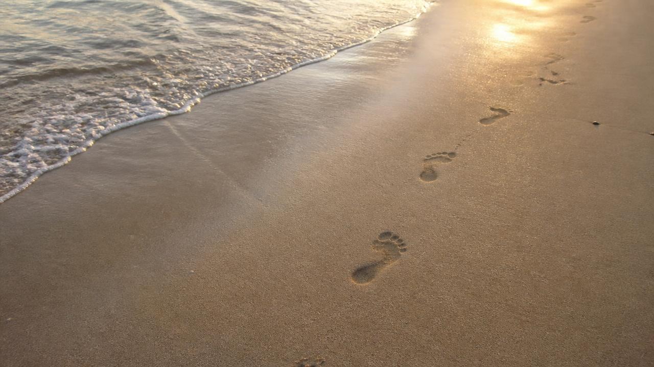 Fußspuren im Sand am Meer im warmen Abendlicht